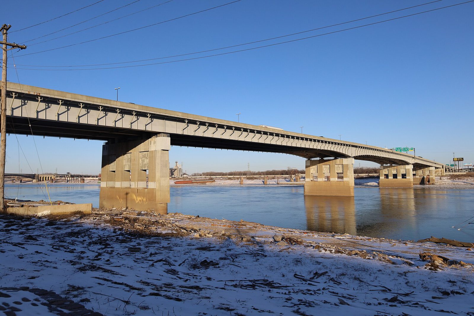 The Poplar Street Bridge crossing the Mississippi River on a clear winter day, concrete piers standing in the water